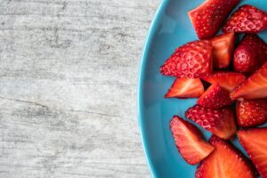 Understanding the Link Between Diet, Exercise, and Mental Well-being sliced strawberries on teal ceramic plate